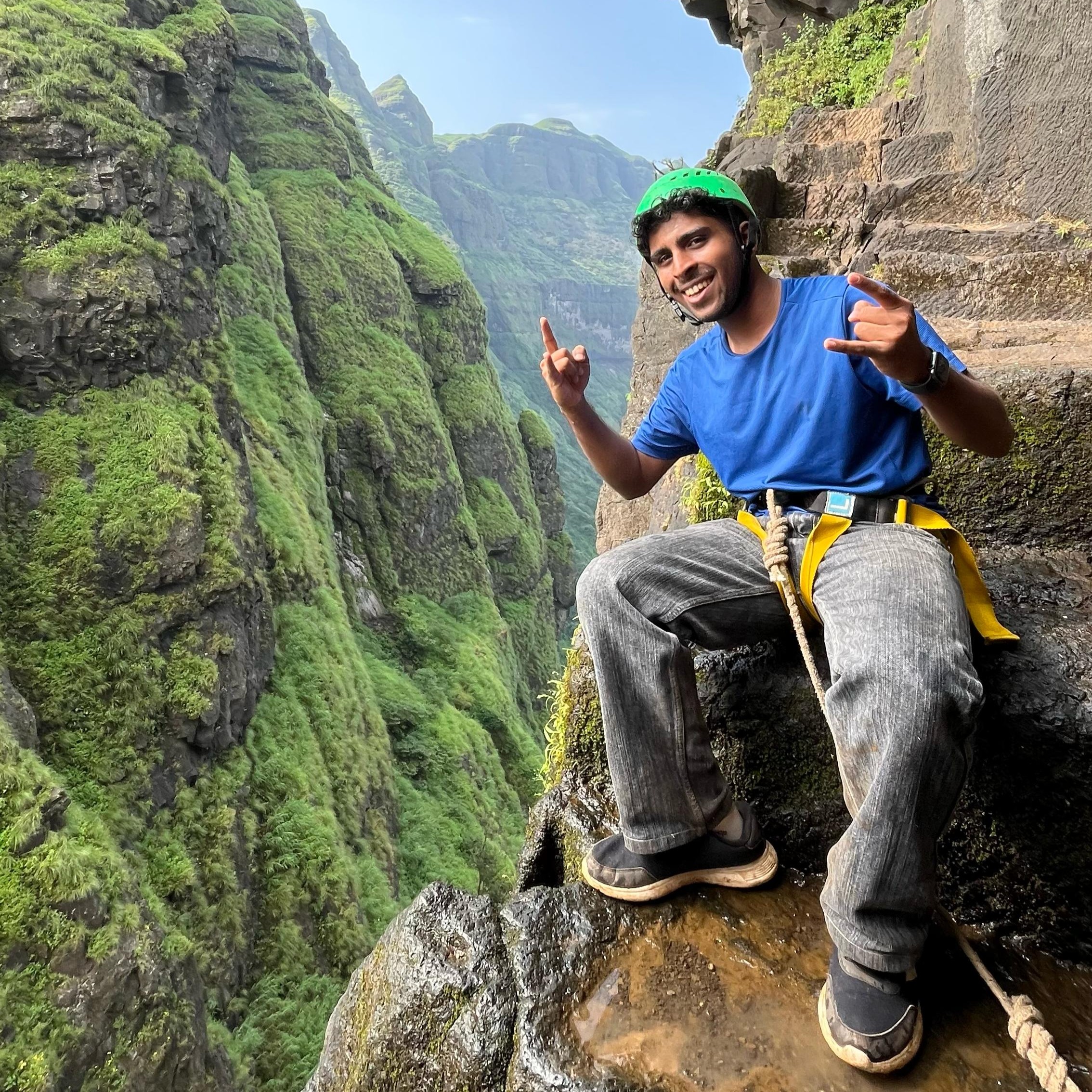 Young man with climbing gear on mountain ledge